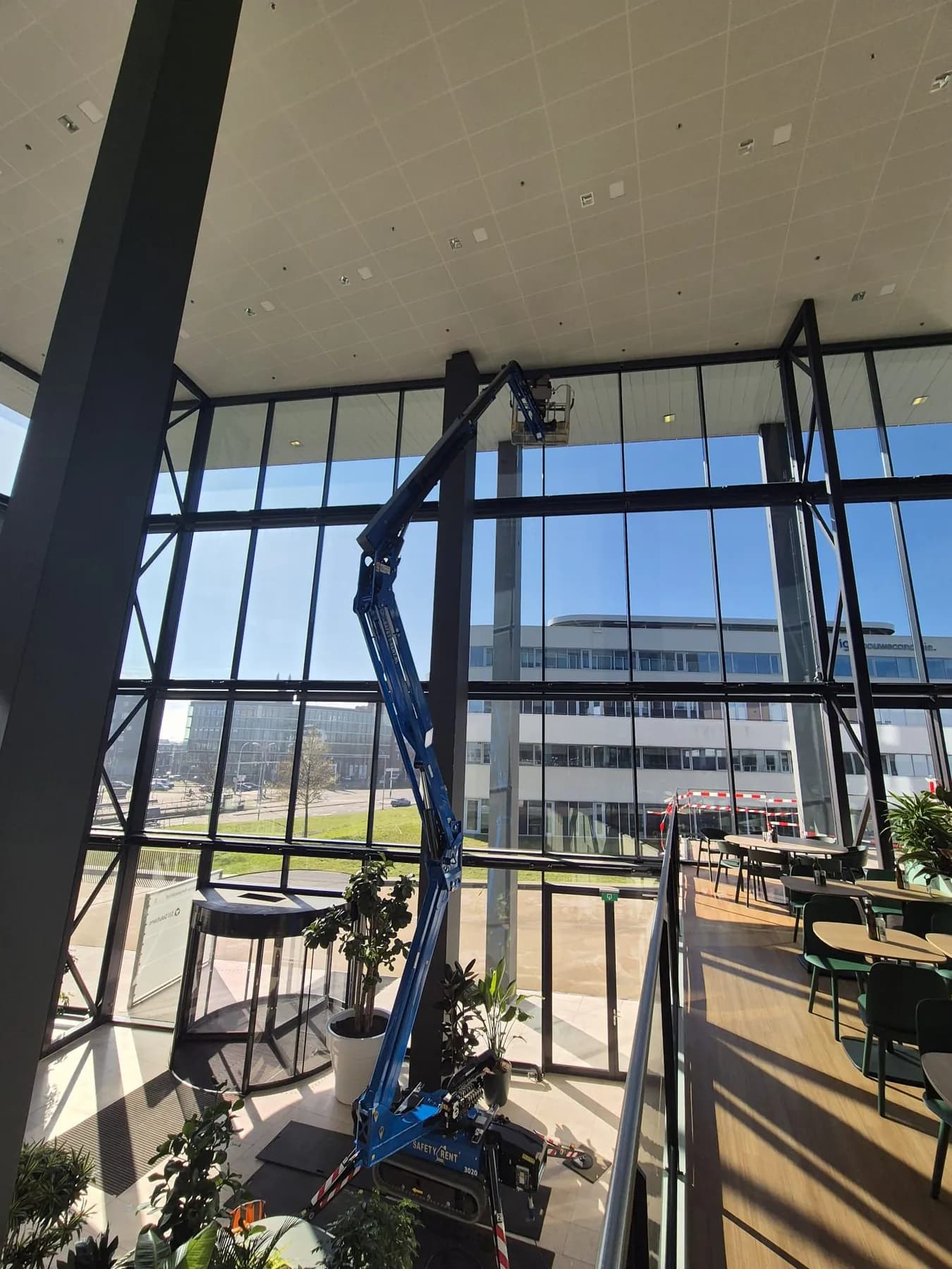 Hoogwerker in een glazen atrium voor het reinigen van hoge ramen aan de binnenzijde