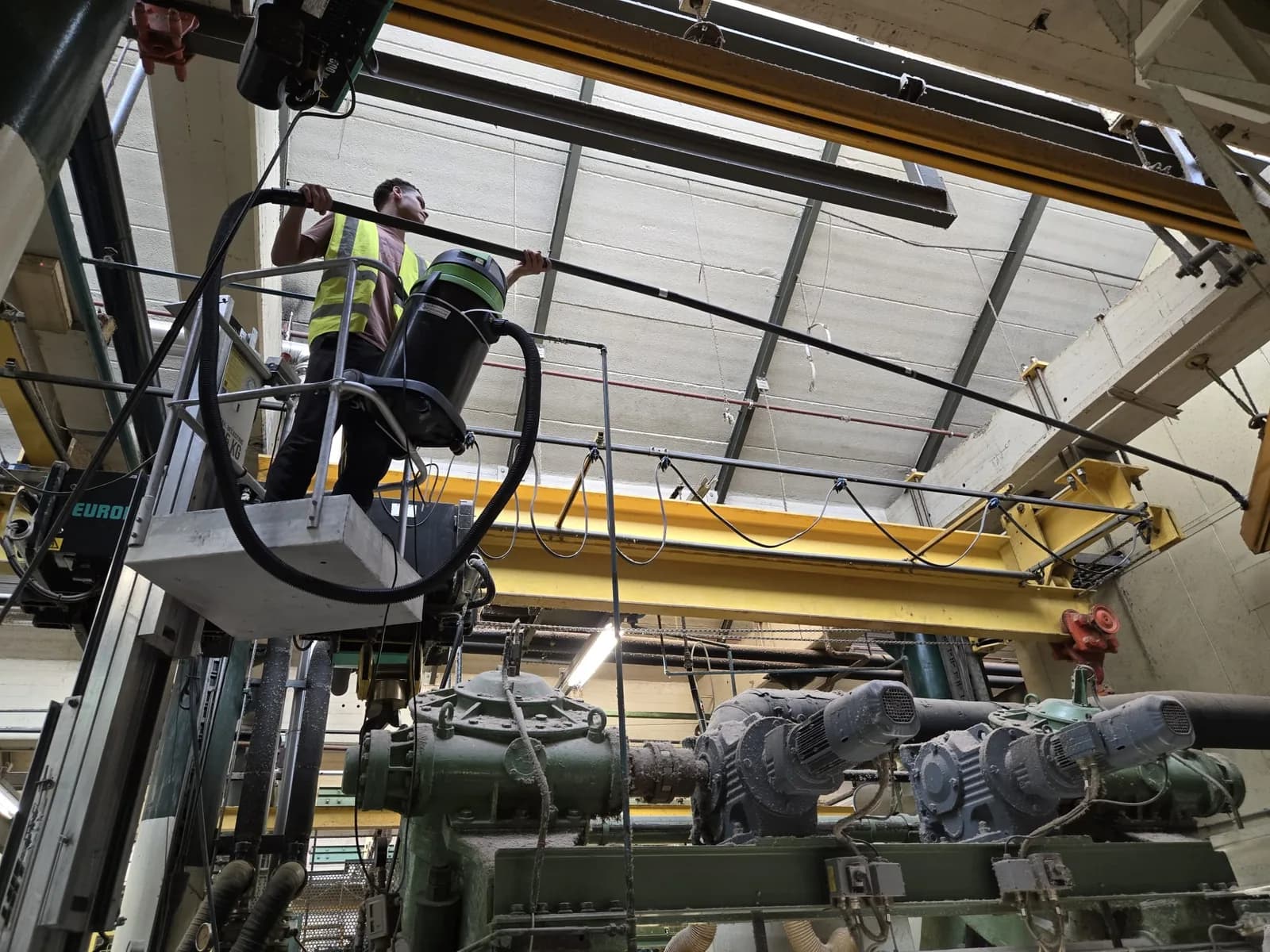 Medewerker reinigt technische installaties vanuit een hoogwerker