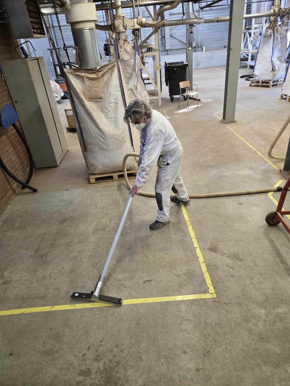 Medewerker reinigt de vloer in een industriële productieomgeving