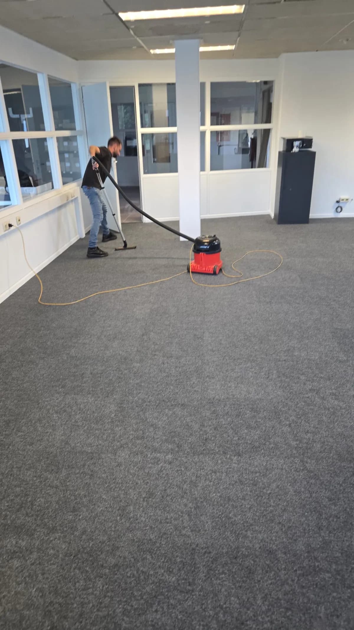 Medewerker stofzuigt de vloer van een kantoorruimte