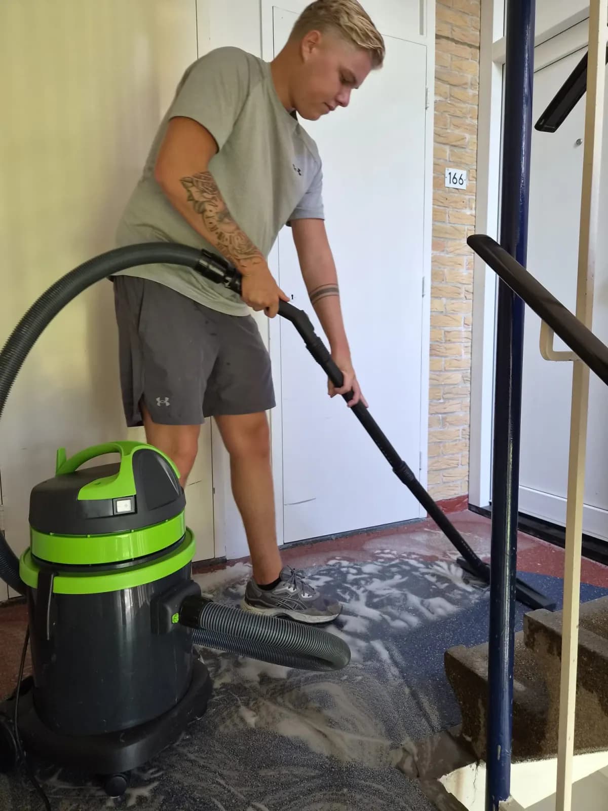 Medewerker reinigt vloerbedekking bij een trappenhuis