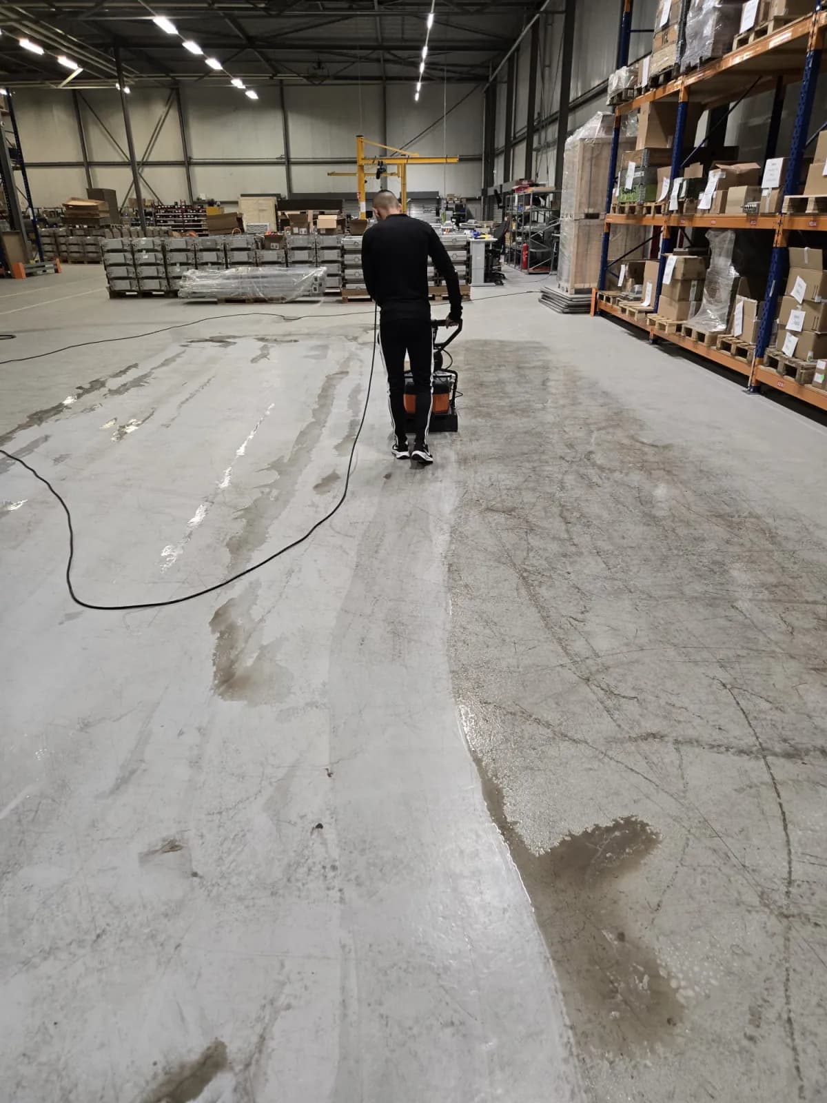 Medewerker reinigt de vloer van een bedrijfshal met een machine